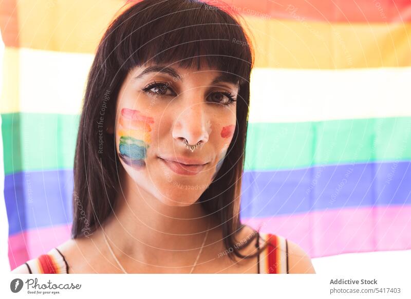 Brünette Frau mit LGBT-Symbol im Gesicht glättet Haare schön lgbt attraktiv jung hübsch sinnlich Freiheit Gleichstellung Rechte heiter Toleranz Regenbogen