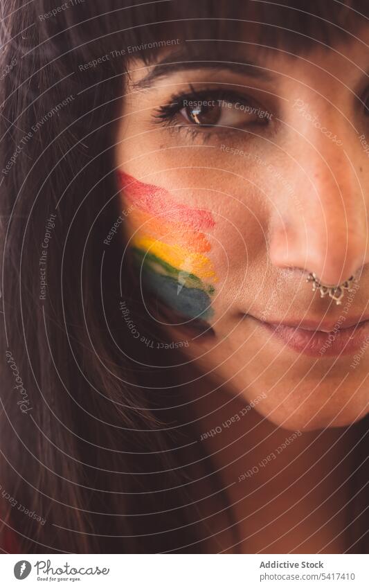 Brünette Frau mit LGBT-Symbol im Gesicht glättet Haare schön lgbt attraktiv jung hübsch sinnlich ernst Freiheit Gleichstellung Rechte Toleranz Regenbogen