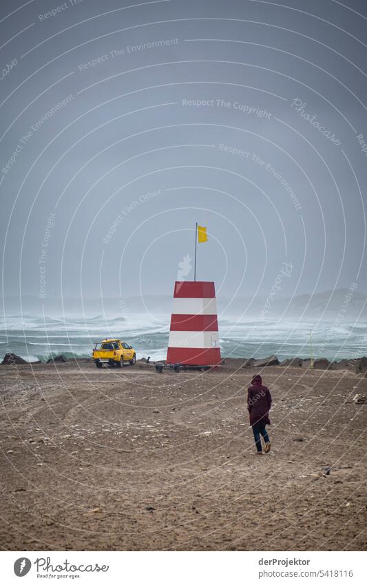 Mensch läuft bei schlechtem Wetter am Strand auf Rettungsturm zu Strukturen & Formen Naturschutzgebiet Gedeckte Farben Textfreiraum links Textfreiraum rechts