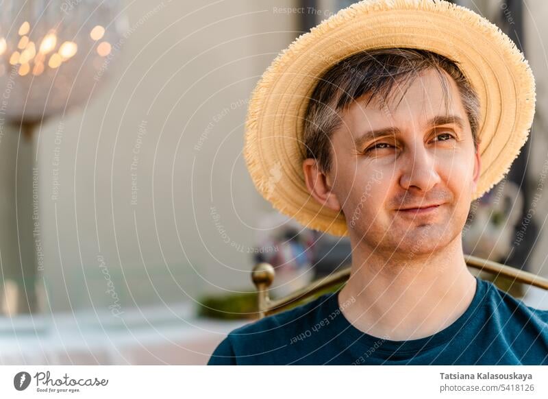 Nahaufnahme eines lächelnden Mannes mittleren Alters, der einen Strohhut und ein T-Shirt trägt Porträt Lächeln Hut Hut Blick lässig Person Kopf heiter