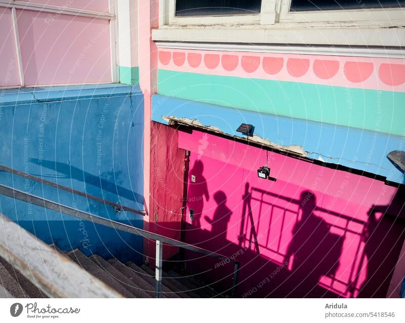 Personenschatten auf bunt bemalter Häuserwand Schatten Menschen Wand Fassade Haus Architektur Blau Pink Sonnenlicht Treppe Stadt Gebäude Außenaufnahme