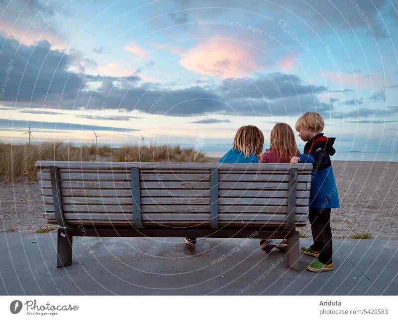 Drei Kinder sitzen auf einer Bank und bewundern den Abendhimmel. … leider stimmt das nicht. Sie schauen auf ein Handy … 🙄 Ostsee Himmel Abendstimmung Wasser