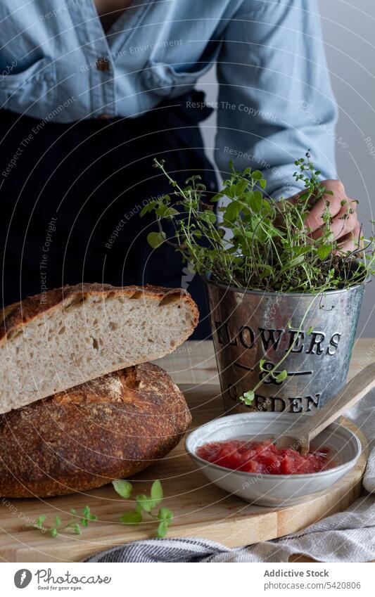 Anonyme Frau berührt Pflanze in der Nähe von Brot Essen zubereiten Sauerteig vorbereitend Belegtes Brot offen Saucen Küche Löffel grün Mahlzeit Lebensmittel