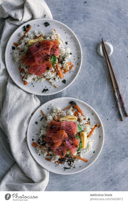 Leckerer Krümelreis mit Lachs und Gemüse auf Leinen mit Stäbchen auf dem Tisch Reis Speise Essstäbchen Asiatische Küche Mahlzeit stoßen frisch Lebensmittel