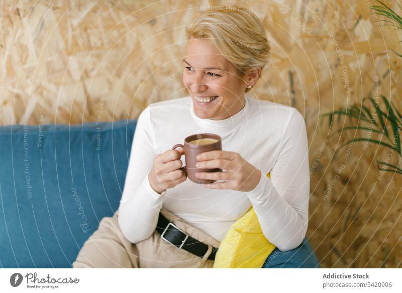 Entspannende Frau mit Kaffeetasse auf Couch ruhen Liege Business Büro Becher Kälte Getränk trinken Freizeit modern lässig Lächeln Tasse Erwachsener Innenbereich