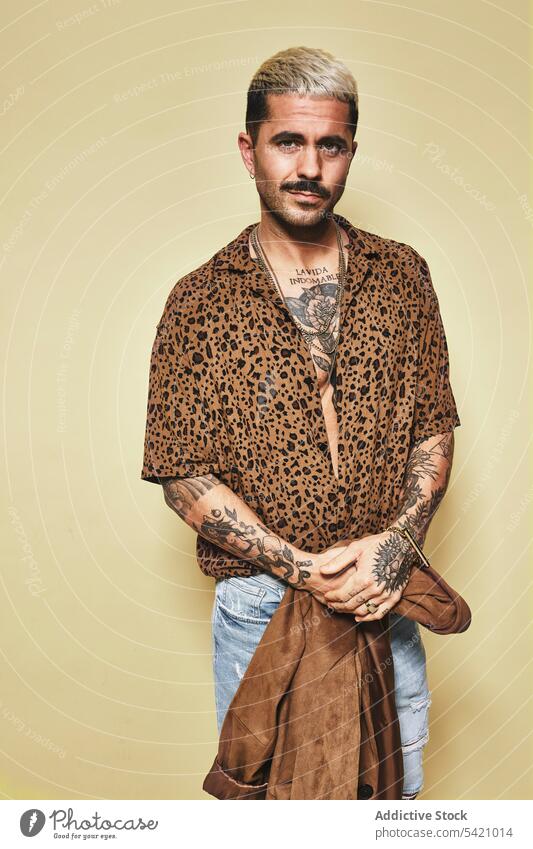 Trendiger ethnischer Typ in modischem Outfit im Studio stehend Mann trendy Stil Mode Leopard Mantel Model Jeanshose Vollbart männlich Stoff modern cool