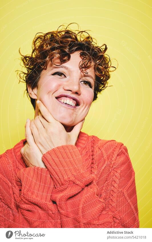 Aufgeregte Frau im warmen Pullover im Studio heiter Glück Überraschung aufgeregt Stil Lachen trendy erstaunt gestrickt krause Haare Freude lässig expressiv
