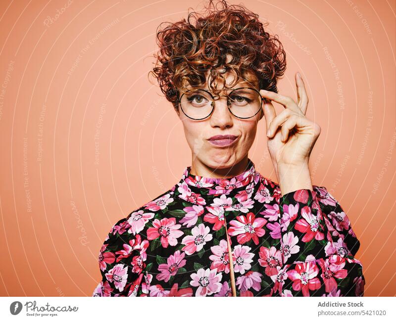 Zweifelnde Frau in trendigem Outfit Mode Stil nachdenklich trendy Brille farbenfroh geblümt jung Model besinnlich Stoff Accessoire krause Haare altehrwürdig