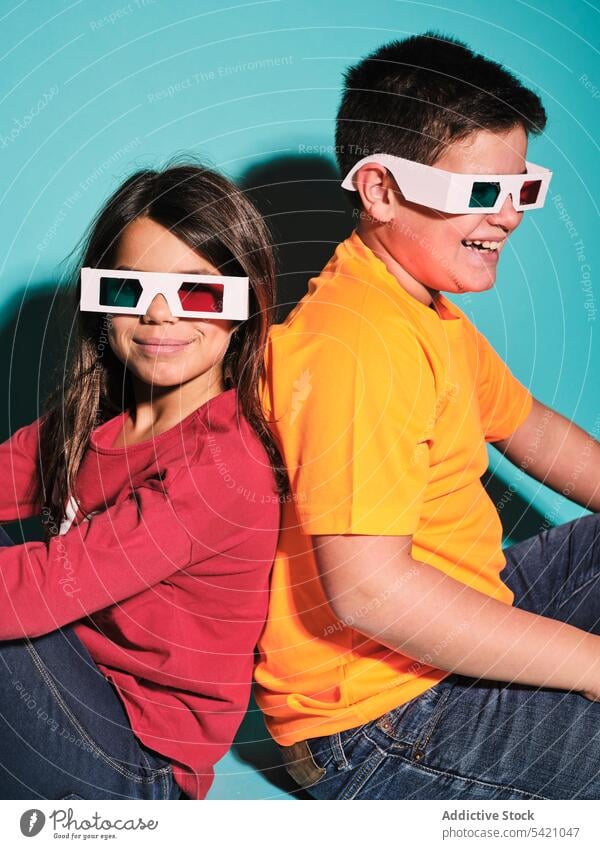 Glückliche trendige Kinder mit 3D-Brille im Studio sitzend dreidimensional Entertainment 3d Spaß Lächeln Freude zuschauen Film Vorstellungskraft heiter