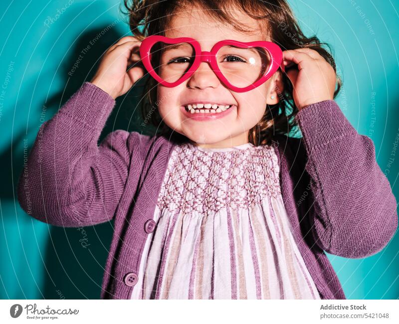 Verspieltes Vorschulkind mit Brille in Herzform Kind Mädchen Vorschule spielerisch Regenbogen Glück Frau positiv Stil heiter Accessoire Kleid Freude
