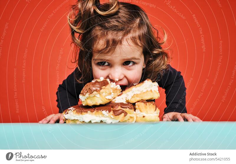 Glückliches Mädchen mit Stapel von Eclairs Kind eclair Bonbon essen Verlangen süß heiter Lebensmittel genießen Haufen wenig lecker ungesund Kalorie Dessert