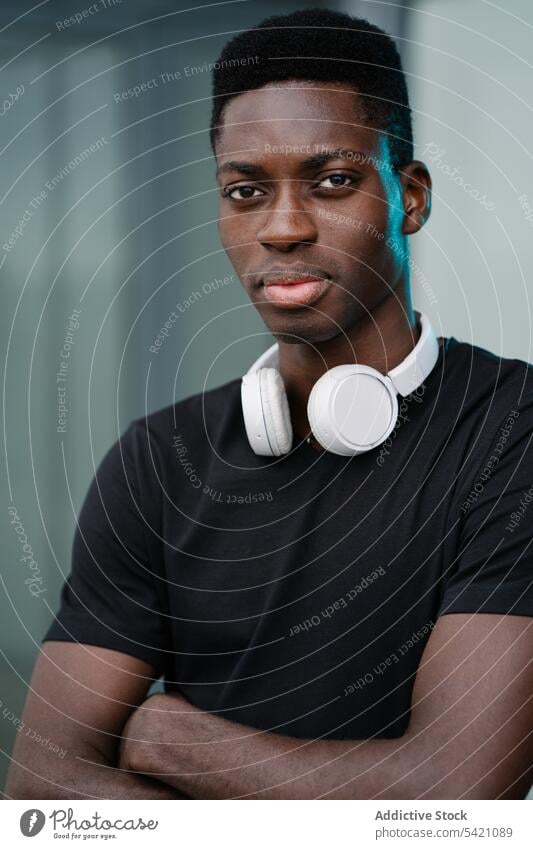 Schwarzer Mann mit Kopfhörern auf der Straße Stirnrunzeln modern urban lässig ethnisch Großstadt männlich Apparatur Gerät ernst schwarz Afroamerikaner Unmut