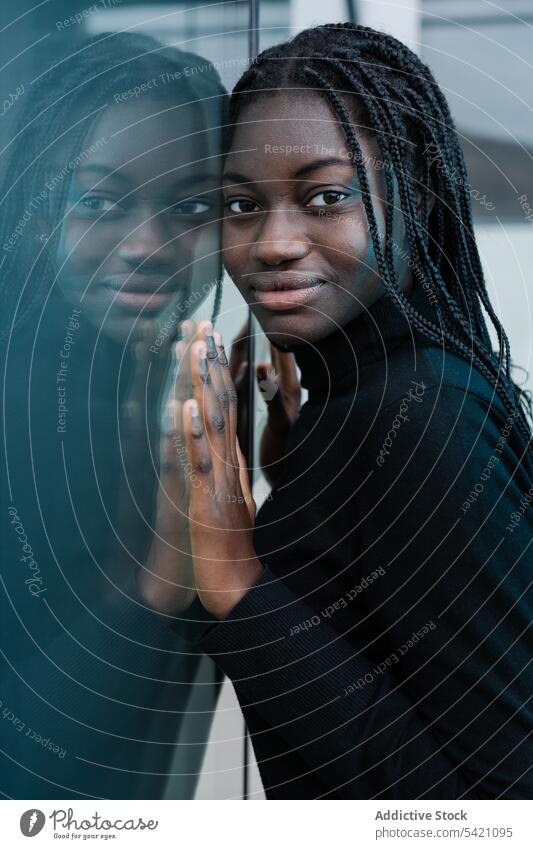 Positive schwarze Frau lehnt an einer Glaswand Straße Großstadt fettarm Wand positiv ethnisch urban lässig Reflexion & Spiegelung froh modern Gebäude Model