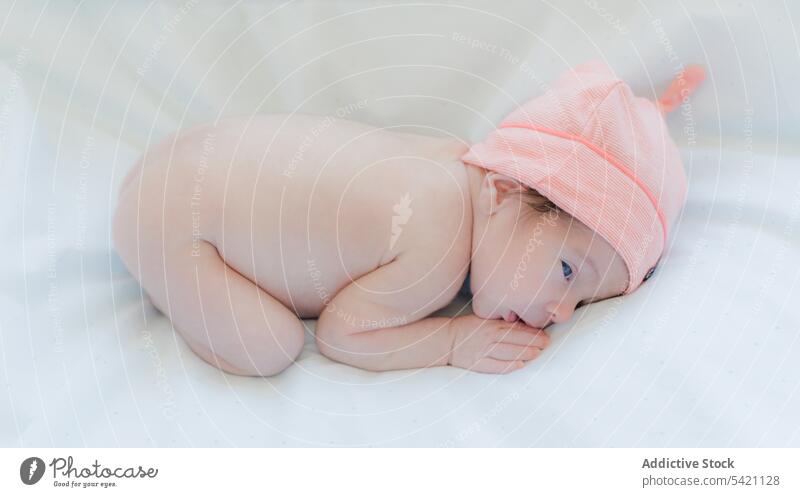 Niedliches Baby in Decke und Hut auf dem Bett liegend neugeboren bezaubernd Kind Lügen umhüllen Porträt winzig rosa süß wenig Säugling Kindheit Kinderbetreuung