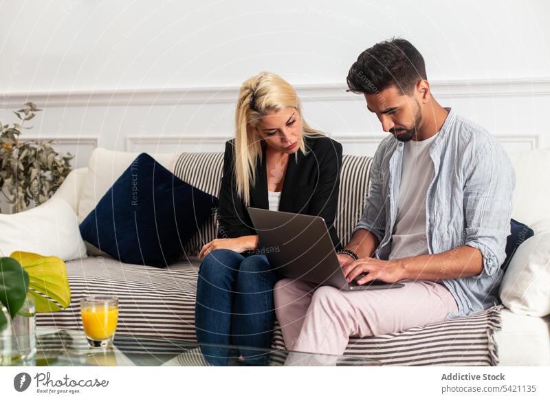 Unterschiedliches Paar benutzt gemeinsam Laptop benutzend heimwärts Sofa Zusammensein vielfältig Wohnzimmer Mann Frau Fokus Computer Liebe Liege zuschauen