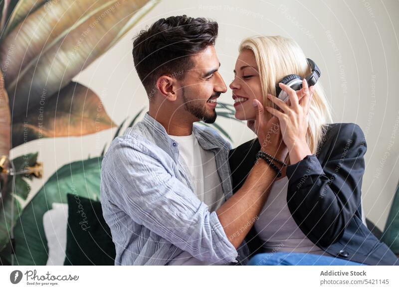 Glückliches Paar beim gemeinsamen Musikhören zuhören Lächeln Zusammensein Liebe Kuss vielfältig Kopfhörer Mann Frau teilen Flirten heimwärts Partnerschaft