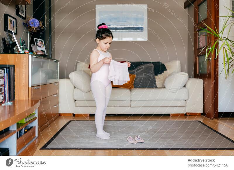 Kleine Ballerina bereitet sich auf das Training zu Hause vor Mädchen vorbereiten heimwärts Wohnzimmer gemütlich angezogen Rock wenig Kind Schuh Trikot