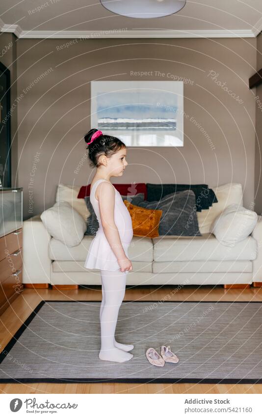 Kleine Ballerina bereitet sich auf das Training zu Hause vor Mädchen vorbereiten heimwärts Wohnzimmer gemütlich angezogen Rock wenig Kind Schuh Trikot