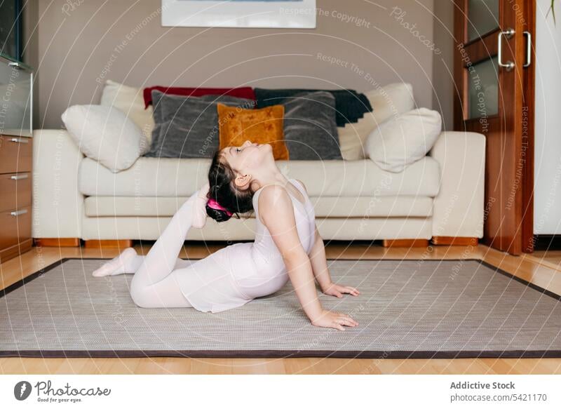 Flexibler kleiner Turner beim Training zu Hause Mädchen beweglich heimwärts Stock Wohnzimmer Übung gemütlich wenig gymnastisch Dehnung Kind Wegbiegung Tastkopf