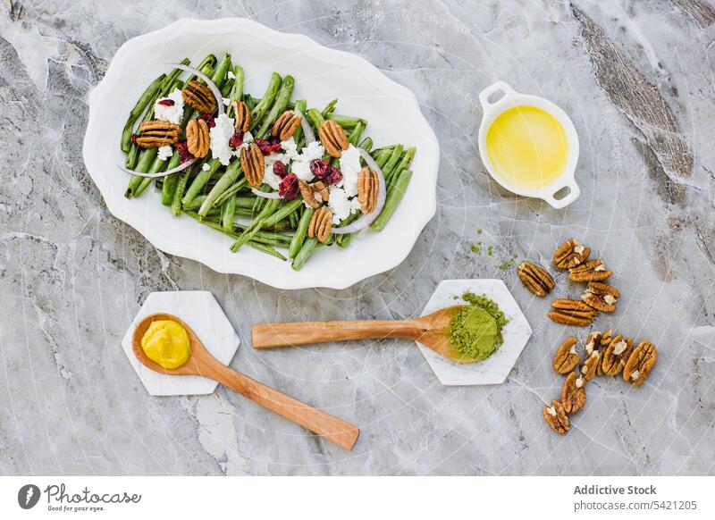 Salat mit grünen Bohnen und Nüssen auf dem Marmortisch Salatbeilage Vegetarier Pekannuss Gemüse Ziegenkäse Gewürz Dressing Bestandteil mischen Teller oliv Nut