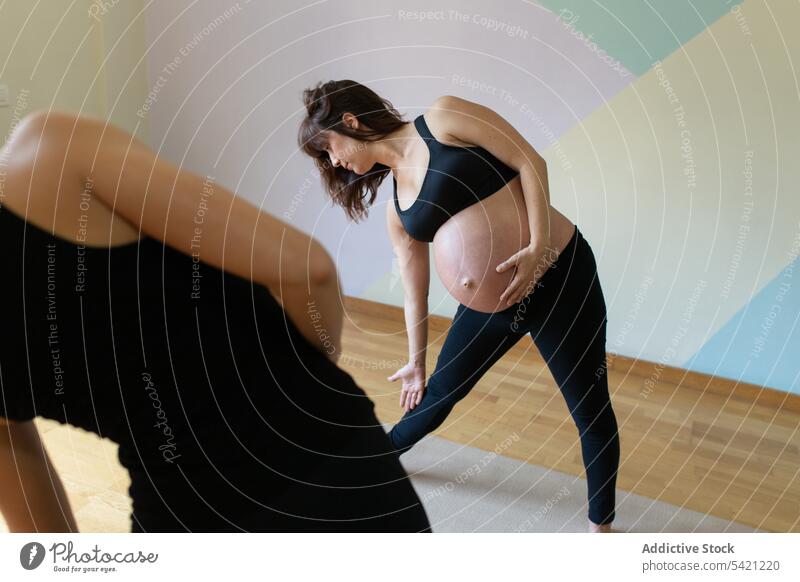 Yogalehrer hilft schwangerer Frau bei Yogaübungen Frauen Atelier Trainerin Triangel-Pose Hilfsbereitschaft Training Übung Zusammensein Gesundheit Wellness üben
