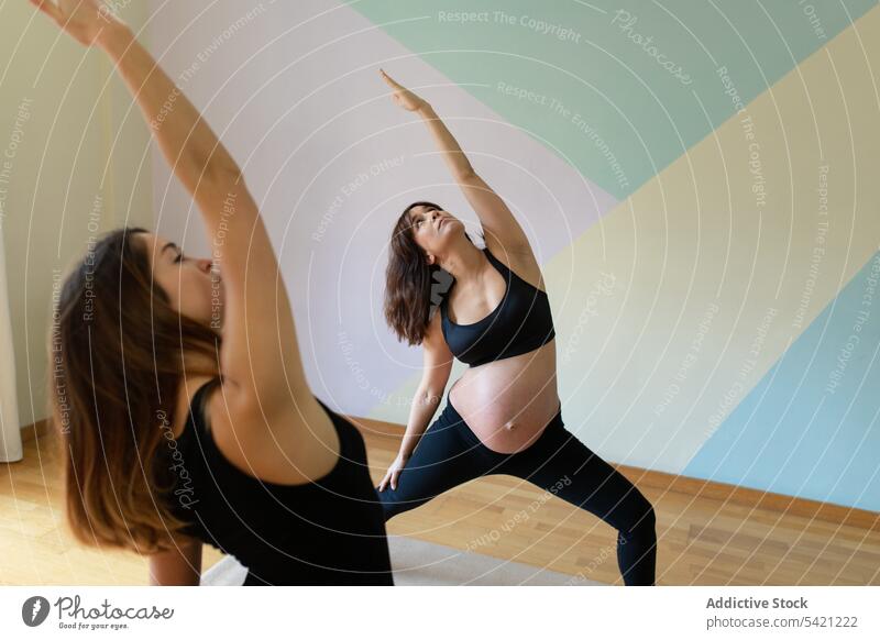 Schwangere Frau beim Yoga mit Trainer Frauen Atelier Trainerin schwanger umgekehrte Krieger-Pose Wiederholen Sie Training Übung Zusammensein Gesundheit Wellness