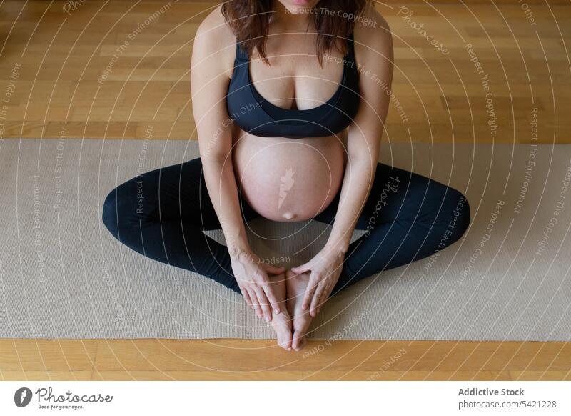 Crop schwangere Frau meditiert auf dem Boden Yoga Meditation Training Lotus-Pose Bauch berühren Gleichgewicht Atelier Sportbekleidung Gesundheit Wellness