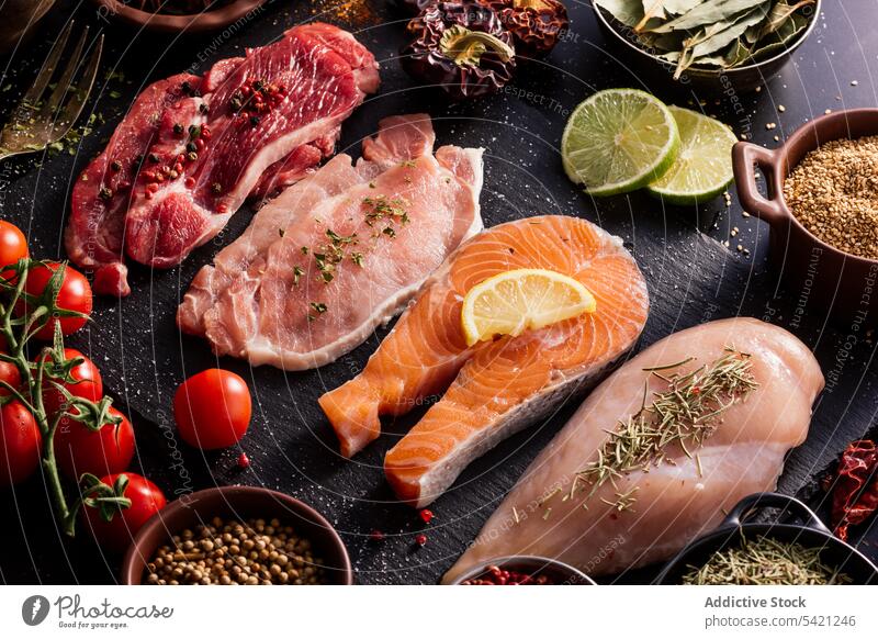 Flache Lage von Proteinen, umgeben von Gewürzen und Würzmitteln auf dem Tisch Produkt Fleisch Lachs Fisch Filet Lebensmittel Paprika Schneidebrett Löffel