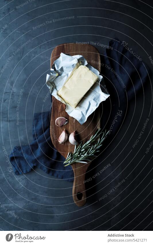 Butterpackung mit aromatischen Gewürzen als traditionelle frische Zutaten für schmackhafte Gerichte auf dem Tisch Rosmarin Knoblauch Schneidebrett rustikal