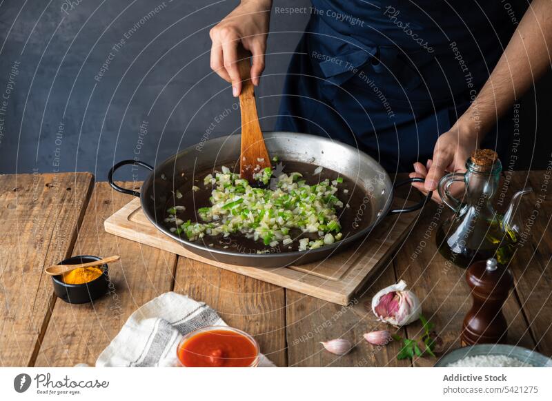 Koch mischt gehackte grüne Chilischoten und Zwiebeln beim Kochen eines schmackhaften Gerichts in der Restaurantküche Pfanne Paprika Erdöl Spachtel rühren Hand