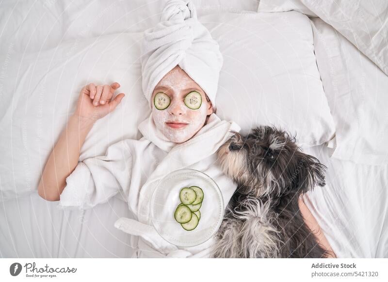 Kind mit Gesichtsmaske auf dem Bett liegend mit Hund Salatgurke Mundschutz Schönheit Hautpflege sich[Akk] entspannen genießen Spa Gesichtsbehandlung natürlich
