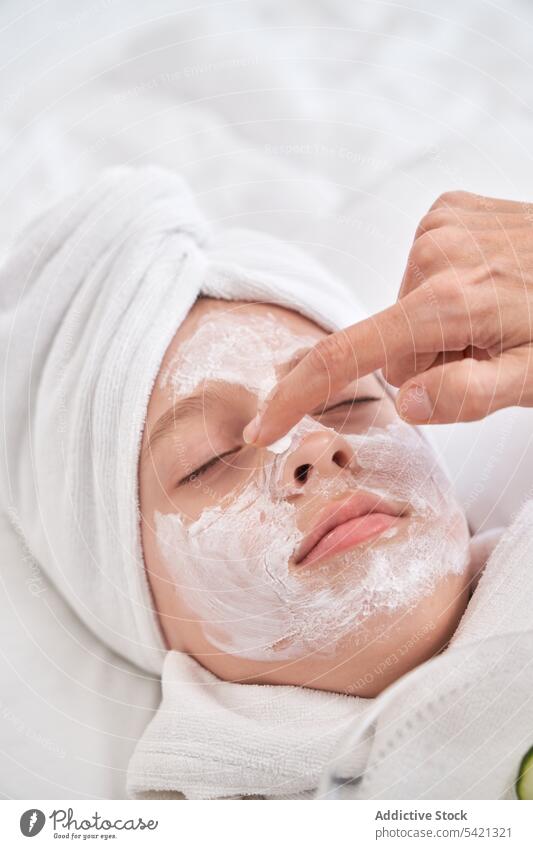 Frau trägt Maske auf das Gesicht eines Kindes auf Schönheit Mundschutz bewerben Salatgurke Hautpflege Spa genießen Verfahren Leckerbissen Gesichtsbehandlung