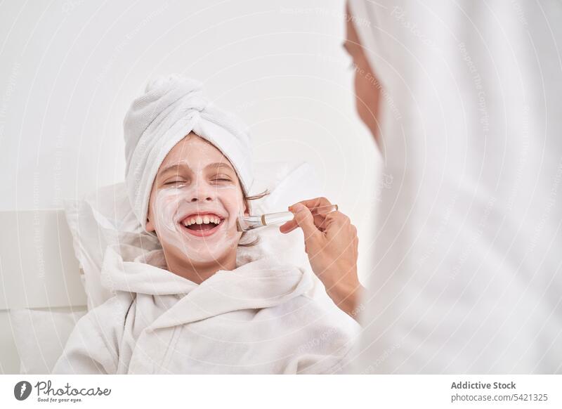Frau trägt Maske auf das Gesicht eines Kindes auf Schönheit Mundschutz bewerben Bürste Salatgurke Hautpflege Spa genießen Verfahren Leckerbissen