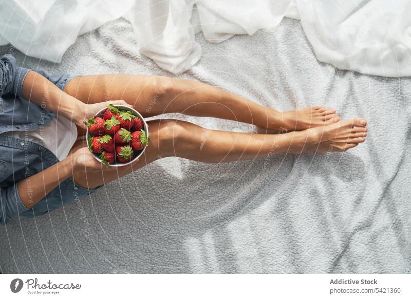 Crop-Frau mit Erdbeeren auf dem Bett sitzend Schalen & Schüsseln heimwärts zeigen Sommer Wochenende reif ruhen Lebensmittel Frucht Beeren Dessert Morgen Decke