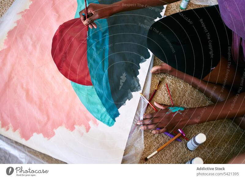 Kreative anonyme Frau malt auf Papier Farbe Bürste heimwärts lässig zeichnen farbenfroh kreativ Ernte Hobby Künstler Afroamerikaner schwarz Amateur Freizeit