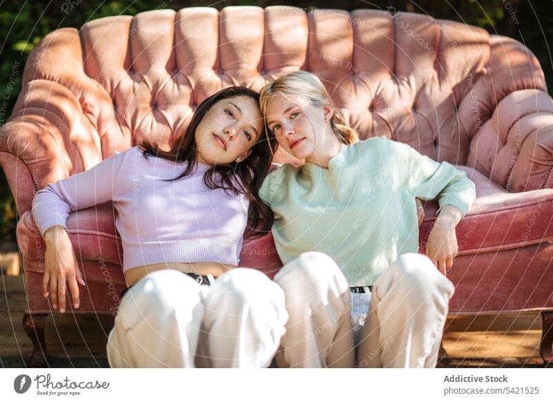 Zarte Teenager-Schwestern sitzen in der Nähe von Sofa im Garten Angebot Geschwisterkind Bonden charmant Gelassenheit sich[Akk] entspannen ruhen Zusammensein