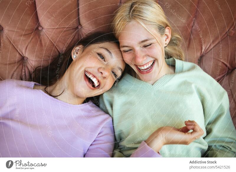 Vergnügte Teenager-Schwestern liegen auf dem Sofa und lachen Spaß haben Lachen heiter Zusammensein Bonden Kälte unterhalten Wochenende Glück Inhalt Lügen Liege