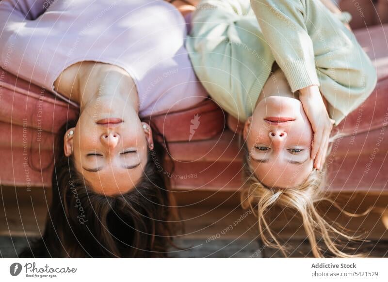 Unbekümmerte Schwestern im Teenageralter, die zusammen auf dem Sofa liegen Angebot Gelassenheit Geschwisterkind auf den Kopf gestellt sorgenfrei charmant Bonden
