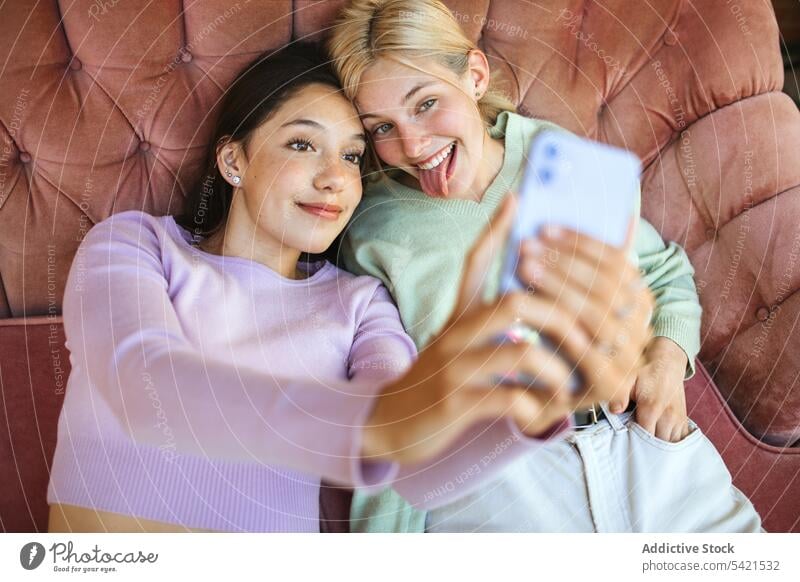 Zufriedene Teenager-Schwestern machen ein Selfie mit ihrem Smartphone auf der Couch Selbstportrait Mädchen Mobile Telefon Angebot jung Sofa benutzend Lügen