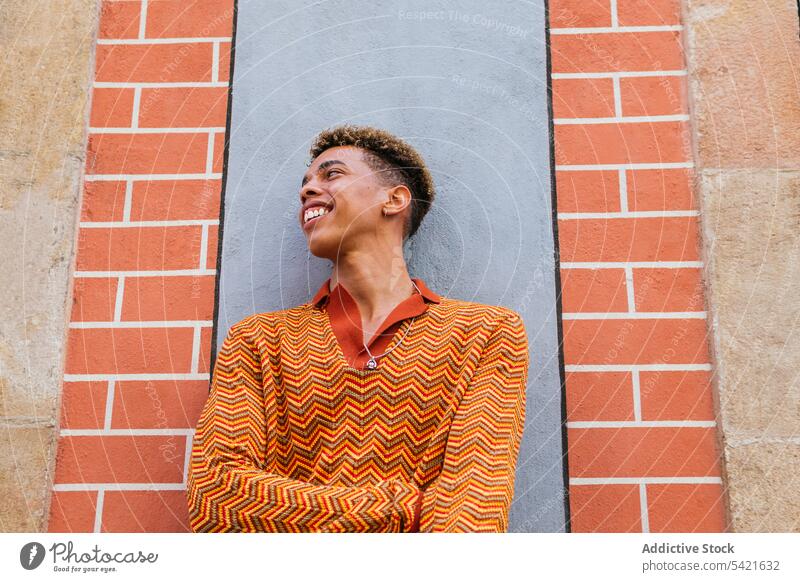 Lächelnder ethnischer Mann auf der Straße Stil Farbe urban orange benutzend modern jung männlich trendy Lifestyle Hipster Scheinwerfer farbenfroh tausendjährig