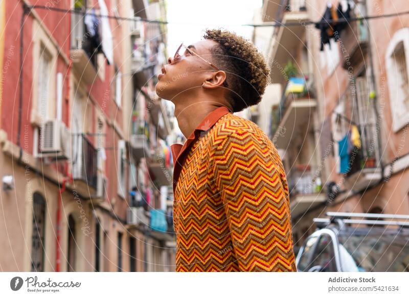 Stilvoller ethnischer Mann auf der Straße in der Stadt Reisender urban selbstbewusst zuhören trendy erkunden männlich jung hispanisch Tourist Urlaub Lifestyle