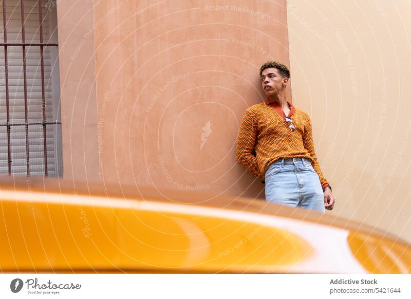Ethnischer Mann steht in der Nähe eines modernen Autos Stil Farbe PKW urban orange Automobil benutzend jung männlich ethnisch trendy Lifestyle Apparatur Hipster