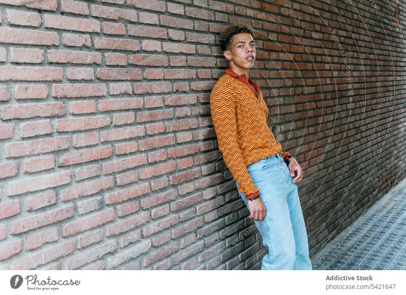 Nachdenklicher ethnischer Mann auf der Straße Stil Farbe urban orange benutzend modern jung männlich trendy Lifestyle Hipster Scheinwerfer farbenfroh