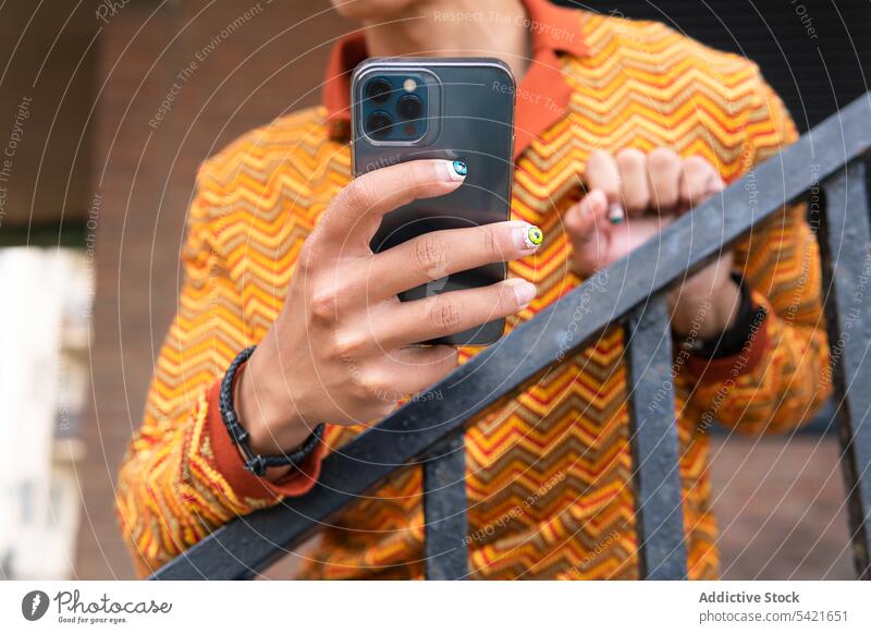 Schicker Mann mit Maniküre und Smartphone Stil nageln ausgefallen benutzend Apparatur Telefon modern männlich Mobile Gerät Browsen trendy Internet Anschluss
