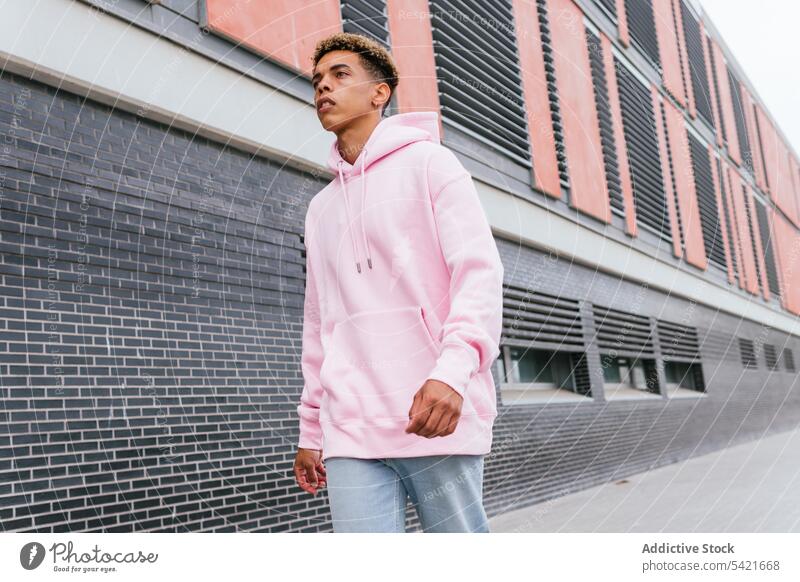 Hipster ethnischer Mann im Kapuzenpulli auf der Straße Stil rosa trendy urban modern Farbe Outfit jung Afro-Look gefärbtes Haar selbstbewusst tausendjährig