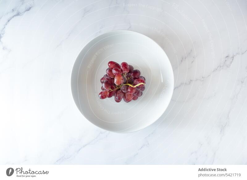 Reifer Traubenzweig auf Teller auf Tisch rosa Haufen Ast Frucht frisch süß sehr wenige Stil natürlich geschmackvoll Lebensmittel lecker organisch dienen Vitamin