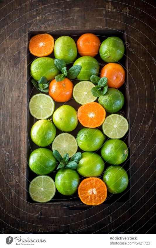 Limetten und Orangen in einem Behälter auf einem Holztisch Kalk orange Kasten Container Ernte Zitrusfrüchte gesunde Ernährung reif frisch roh sauer Frucht Tisch