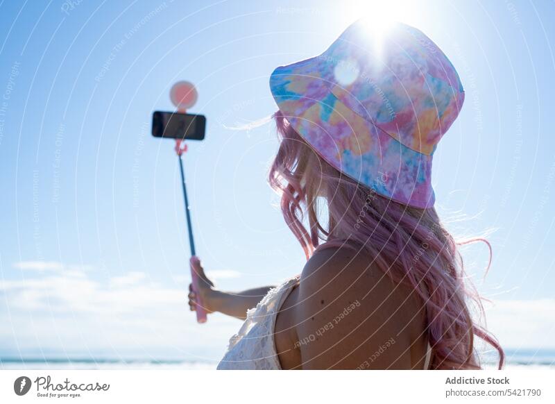 Anonyme Frau mit rosa Haaren macht Selfie am Strand Sommer Selfie-Stick Smartphone Selbstportrait Meeresufer heiter Spaß haben fotografieren Lächeln Apparatur