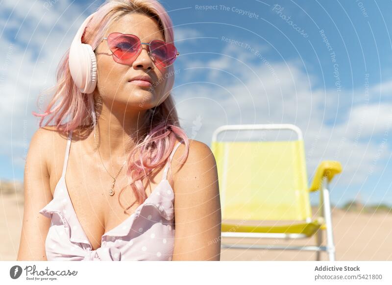 Frau hört Musik am Strand im Sommer zuhören Kopfhörer sorgenfrei Kälte Sommerzeit Seeküste rosa Haare sich[Akk] entspannen genießen Windstille Inhalt ruhig