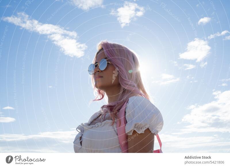 Stilvolle Frau mit rosa Haaren steht gegen das Meer im Sommer MEER Urlaub Feiertag trendy Sonnenbrille Sommerzeit Wasser Blauer Himmel Küste Freiheit Erholung